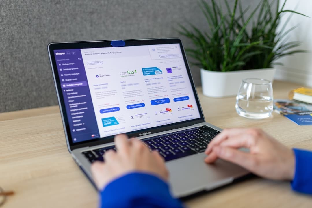 Hands typing on laptop's keyboard. On the computer we can see Shoper AppStore