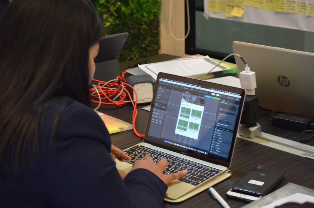 Web designer working on a laptop with wireframe designs